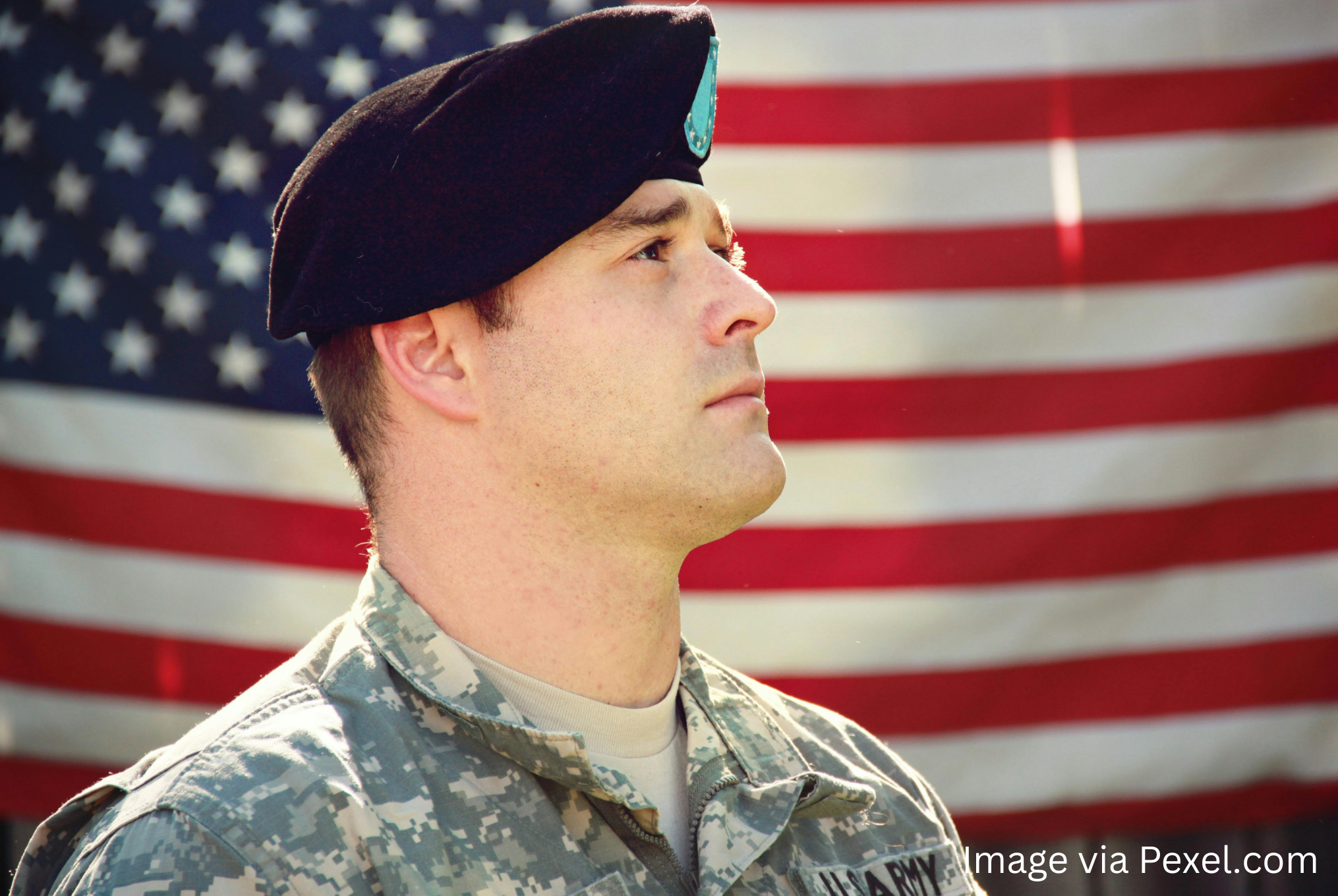 Soldier standing in front of flag.